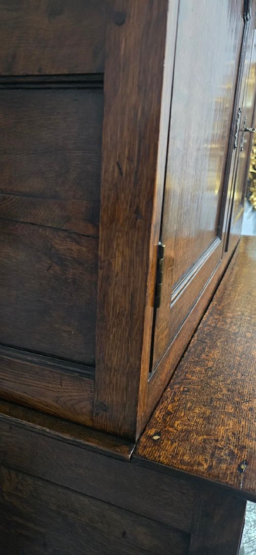 A dark oak Georgian court cupboard featuring an upper cabinet with arched panel doors, two central drawers, and a lower double-door cupboard on bracket feet. View XI