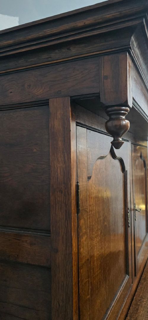 A dark oak Georgian court cupboard featuring an upper cabinet with arched panel doors, two central drawers, and a lower double-door cupboard on bracket feet. View XII