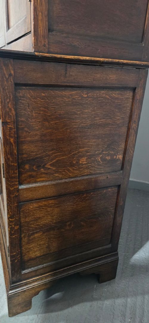 A dark oak Georgian court cupboard featuring an upper cabinet with arched panel doors, two central drawers, and a lower double-door cupboard on bracket feet. View XIII