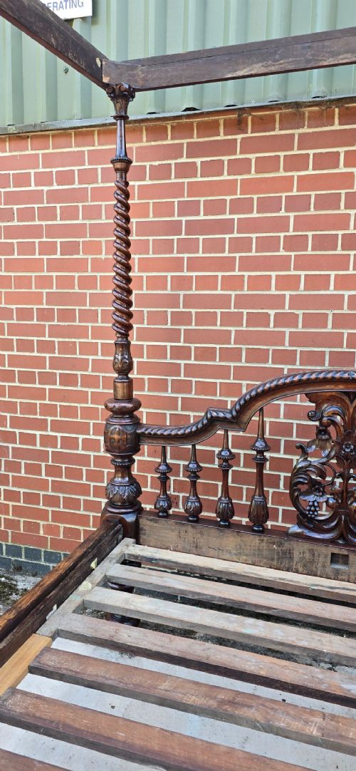 A dark wood four-poster bed frame featuring carved spiral posts, turned spindles, and an arched cresting headboard. View X