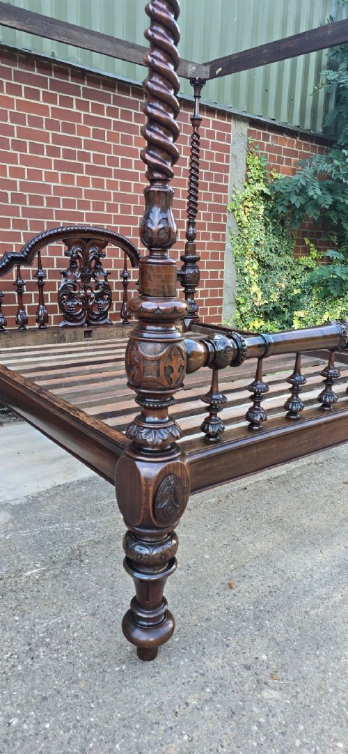 A dark wood four-poster bed frame featuring carved spiral posts, turned spindles, and an arched cresting headboard. View XII