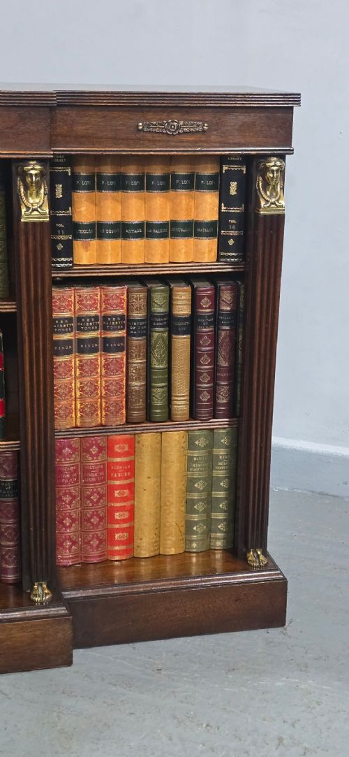 An antique Empire style breakfront low mahogany bookcase featuring three sections of open adjustable shelves filled with books and adorned with gilt bronze mounts and fluted pilasters. View VI