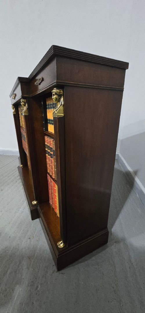 An antique Empire style breakfront low mahogany bookcase featuring three sections of open adjustable shelves filled with books and adorned with gilt bronze mounts and fluted pilasters. View XI