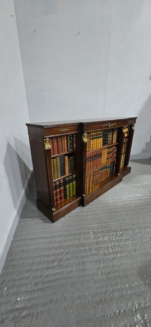 An antique Empire style breakfront low mahogany bookcase featuring three sections of open adjustable shelves filled with books and adorned with gilt bronze mounts and fluted pilasters. View XIII