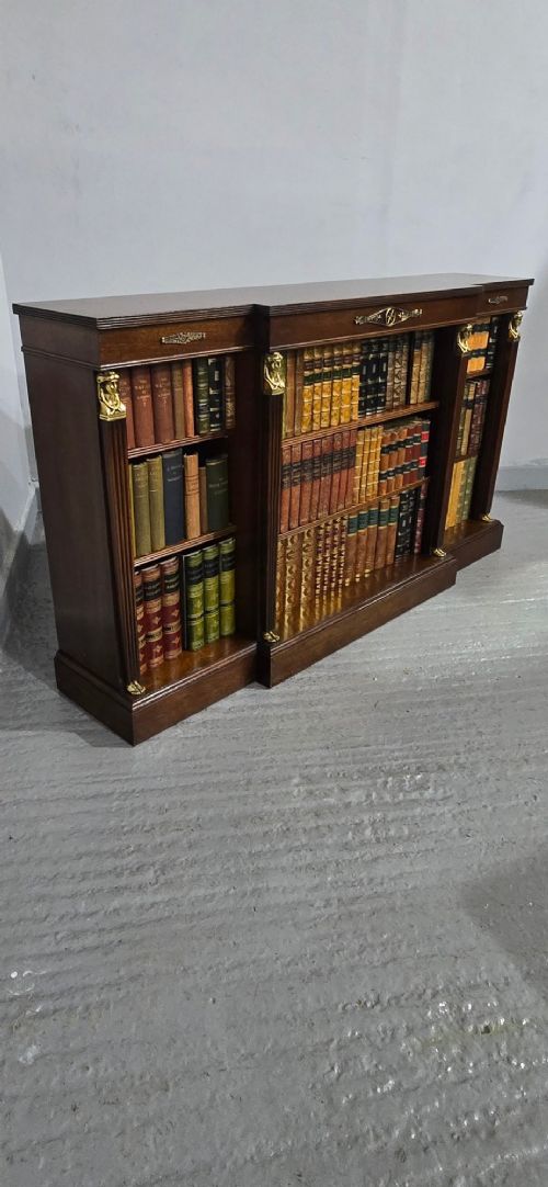 An antique Empire style breakfront low mahogany bookcase featuring three sections of open adjustable shelves filled with books and adorned with gilt bronze mounts and fluted pilasters. View XIV