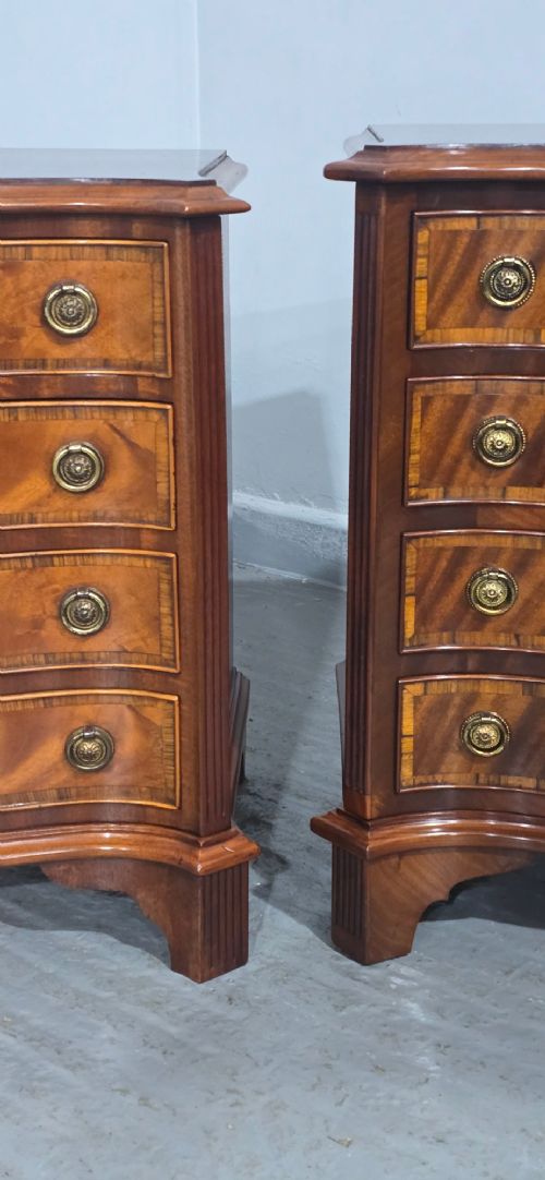 A matching pair of serpentine-fronted mahogany bedside chests, each featuring four drawers with inlay crossbanding and circular brass ring handles. View VI