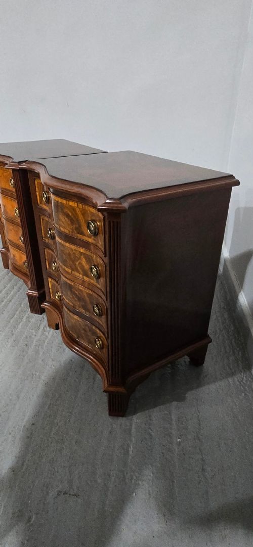 A matching pair of serpentine-fronted mahogany bedside chests, each featuring four drawers with inlay crossbanding and circular brass ring handles. View IX