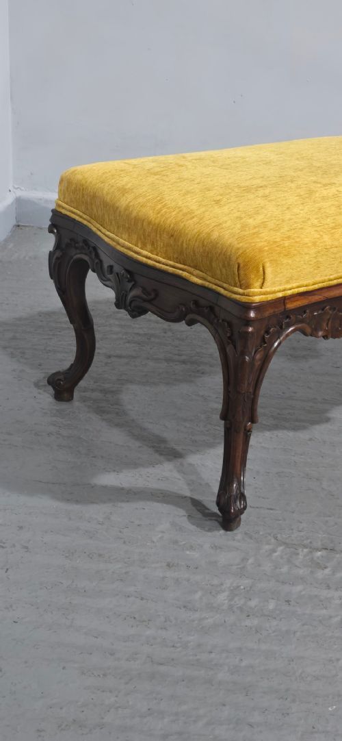 A rectangular Regency period stool featuring a mustard yellow fabric top resting on a dark carved rosewood frame with cabriole legs. View V