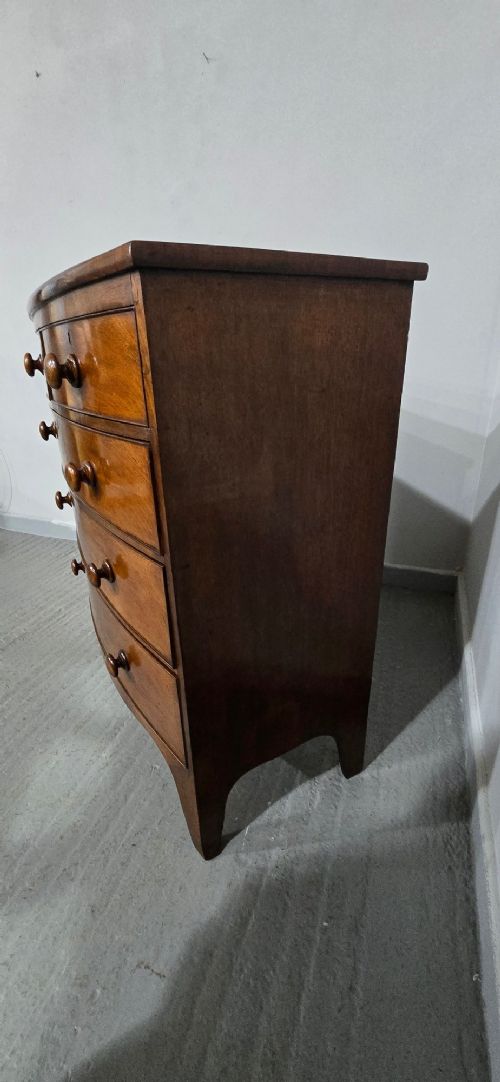 An antique mahogany bow-front chest of drawers featuring two short drawers over three long graduated drawers with turned wooden knobs. View IV