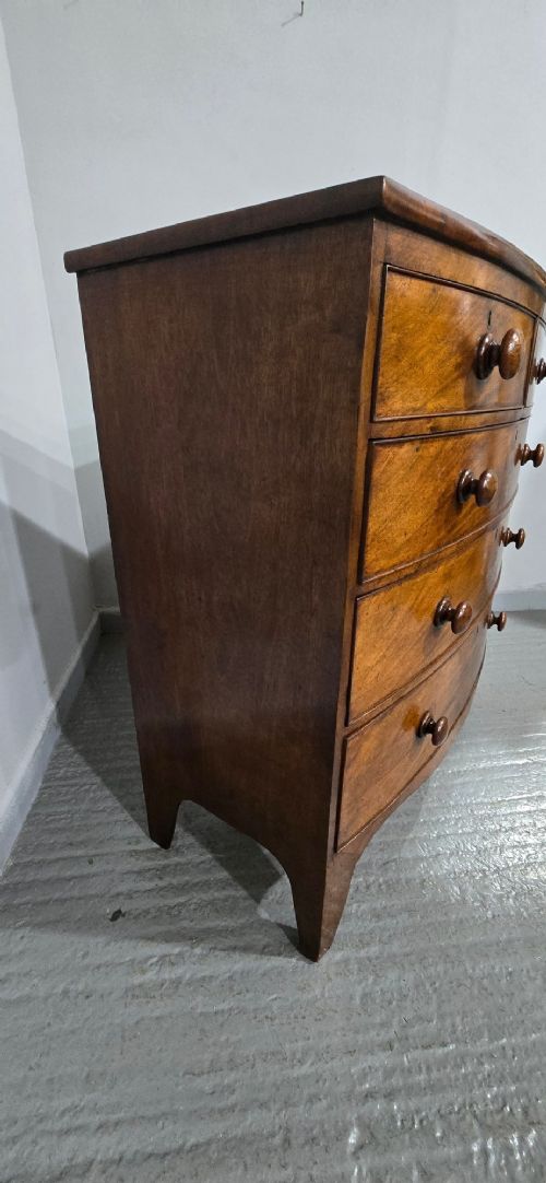 An antique mahogany bow-front chest of drawers featuring two short drawers over three long graduated drawers with turned wooden knobs. View V