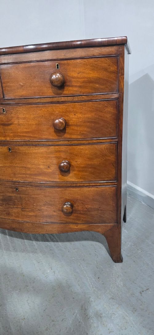 An antique mahogany bow-front chest of drawers featuring two short drawers over three long graduated drawers with turned wooden knobs. View XI