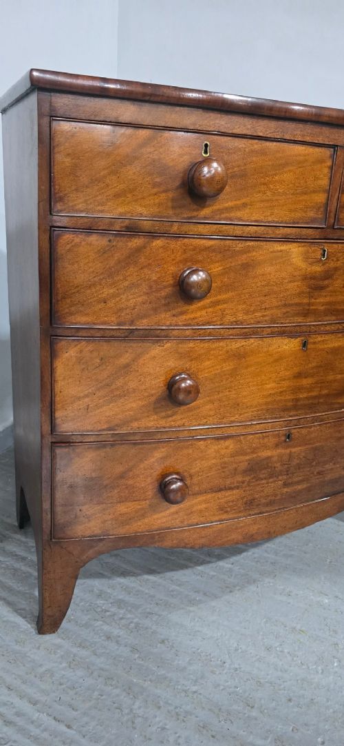 An antique mahogany bow-front chest of drawers featuring two short drawers over three long graduated drawers with turned wooden knobs. View XII