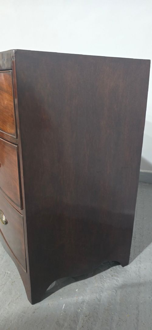 An antique Georgian mahogany bowfront chest featuring three drawers with oval brass handles and keyholes. View VIII