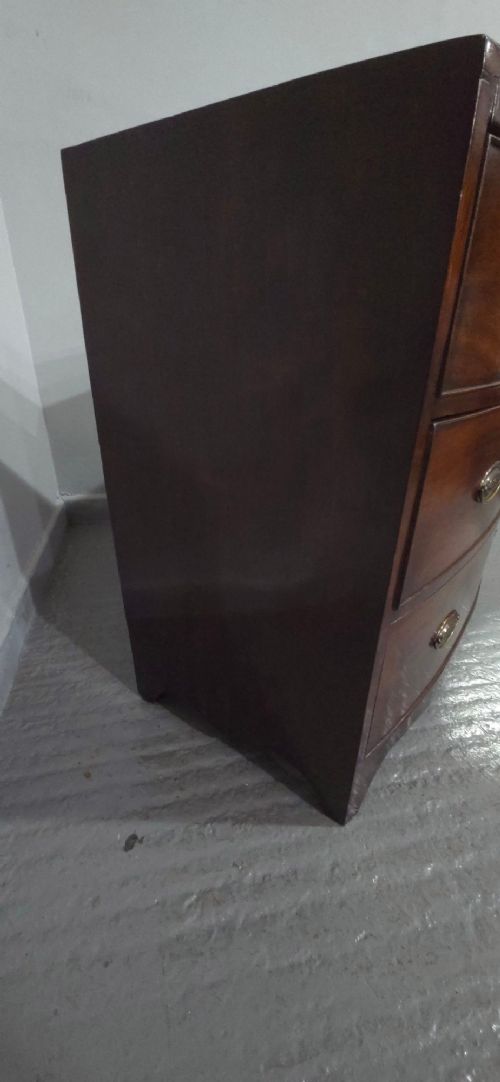 An antique Georgian mahogany bowfront chest featuring three drawers with oval brass handles and keyholes. View X
