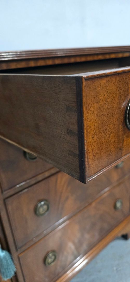 A mahogany bowfront sideboard featuring four central drawers flanked by two curved outer cupboard doors with flame mahogany veneer panels and brass ring handles. View VI