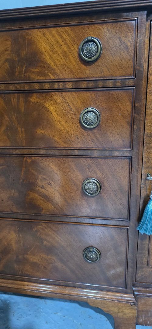 A mahogany bowfront sideboard featuring four central drawers flanked by two curved outer cupboard doors with flame mahogany veneer panels and brass ring handles. View IX
