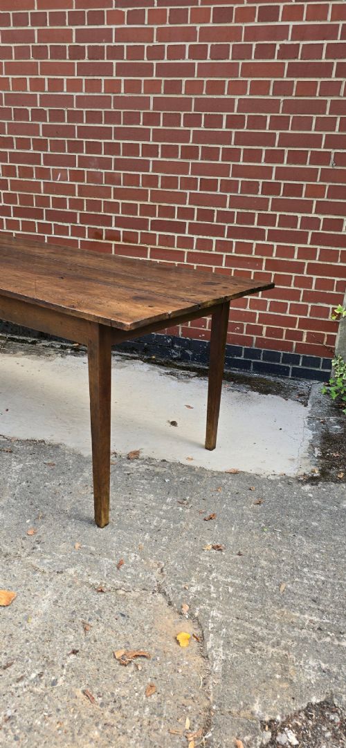 An antique rustic French wooden refectory dining table featuring a three-plank top, single side drawer, and square tapered legs. View V