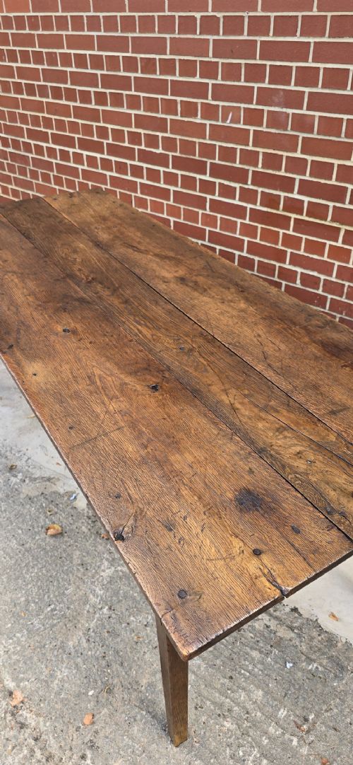 An antique rustic French wooden refectory dining table featuring a three-plank top, single side drawer, and square tapered legs. View IX