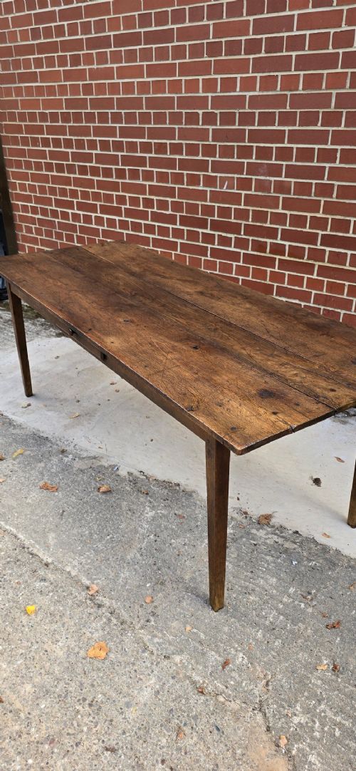 An antique rustic French wooden refectory dining table featuring a three-plank top, single side drawer, and square tapered legs. View X