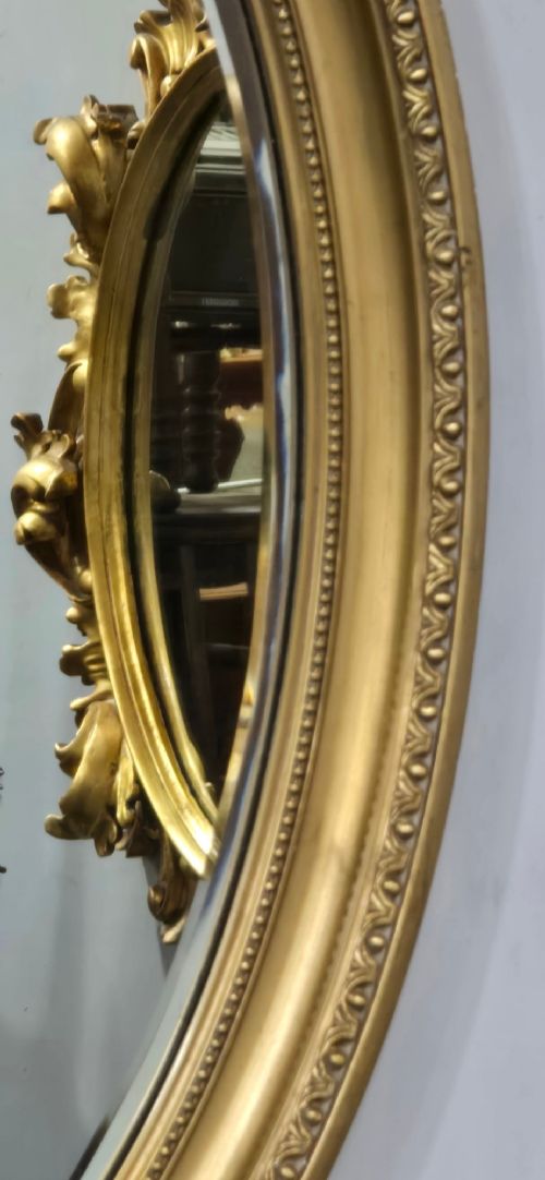 An antique oval wall mirror featuring a gilded frame decorated with beaded and egg-and-dart moulded trim. View VI