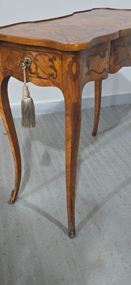 A small French Louis XV style writing table crafted from warm brown wood with scrolling marquetry, a serpentine edge, and slim cabriole legs. View XI