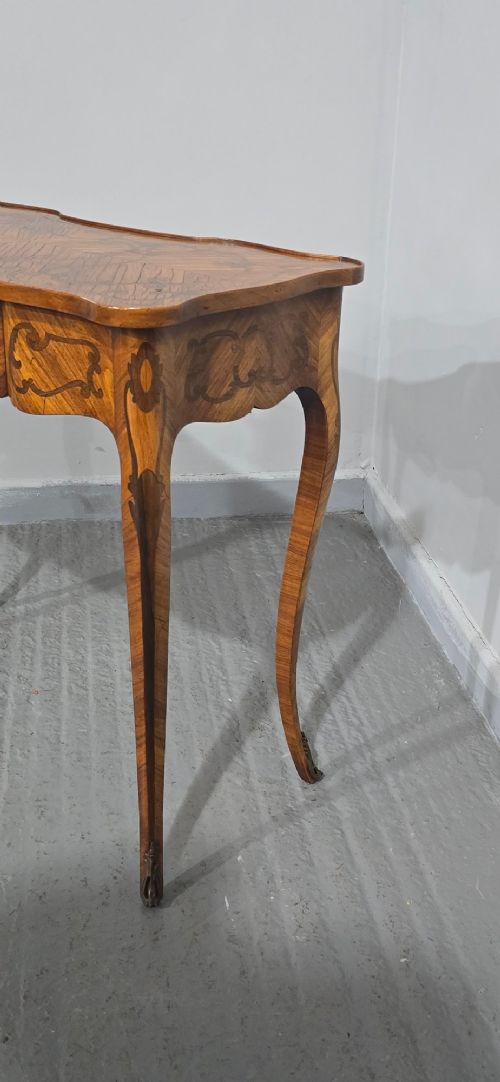 A small French Louis XV style writing table crafted from warm brown wood with scrolling marquetry, a serpentine edge, and slim cabriole legs. View XIII
