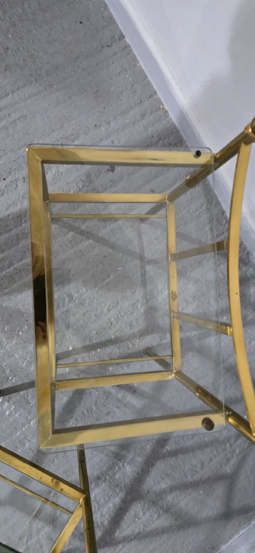Pair of two-tier brass side tables with clear glass shelves and decorative finials. View IX