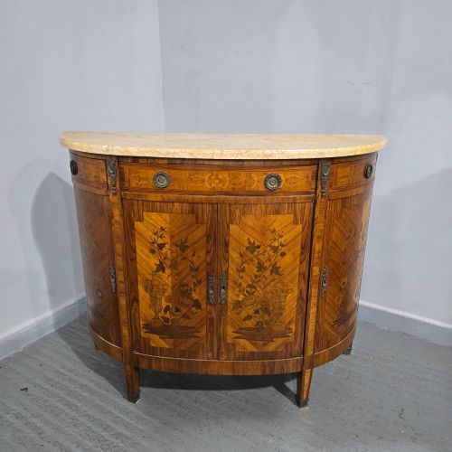 fig 1. A French Louis XVI style demi-lune cabinet featuring intricate floral marquetry inlay, gilt-bronze mounts, and a contoured marble top.
