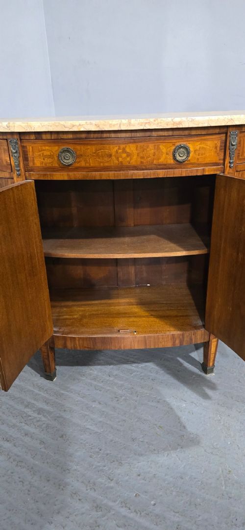 A French Louis XVI style demi-lune cabinet featuring intricate floral marquetry inlay, gilt-bronze mounts, and a contoured marble top. View IX