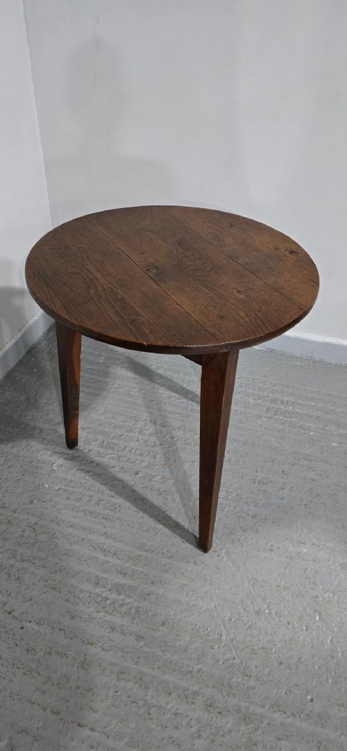 A dark brown Georgian oak cricket table featuring a circular planked top supported by three splayed tapered legs. View III