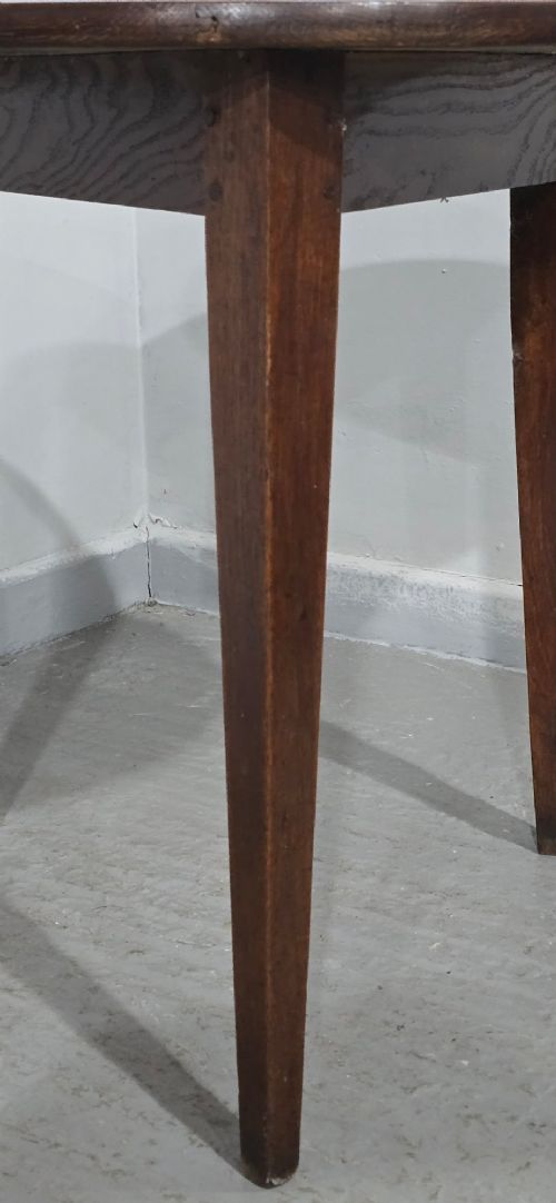 A dark brown Georgian oak cricket table featuring a circular planked top supported by three splayed tapered legs. View VI