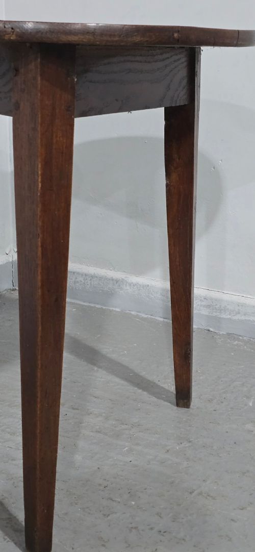 A dark brown Georgian oak cricket table featuring a circular planked top supported by three splayed tapered legs. View VII