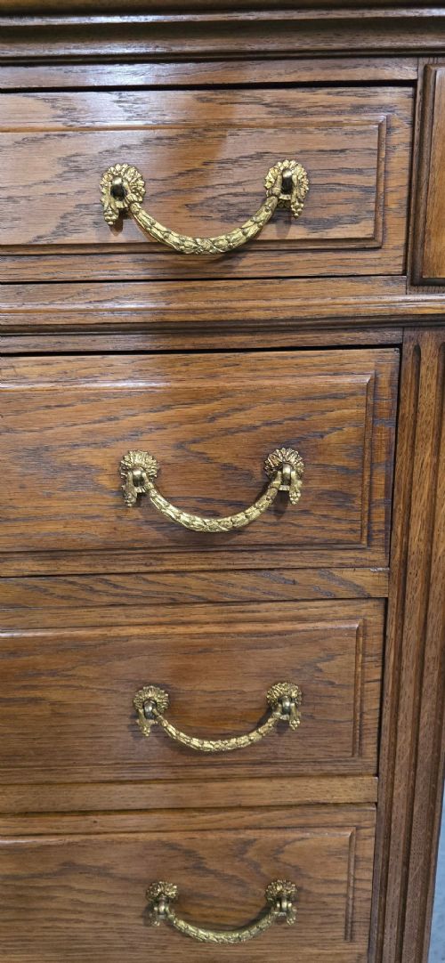 fig 1. A tall French oak chest of drawers featuring six stacked drawers, brass swing handles, fluted side pilasters, and turned wooden feet.