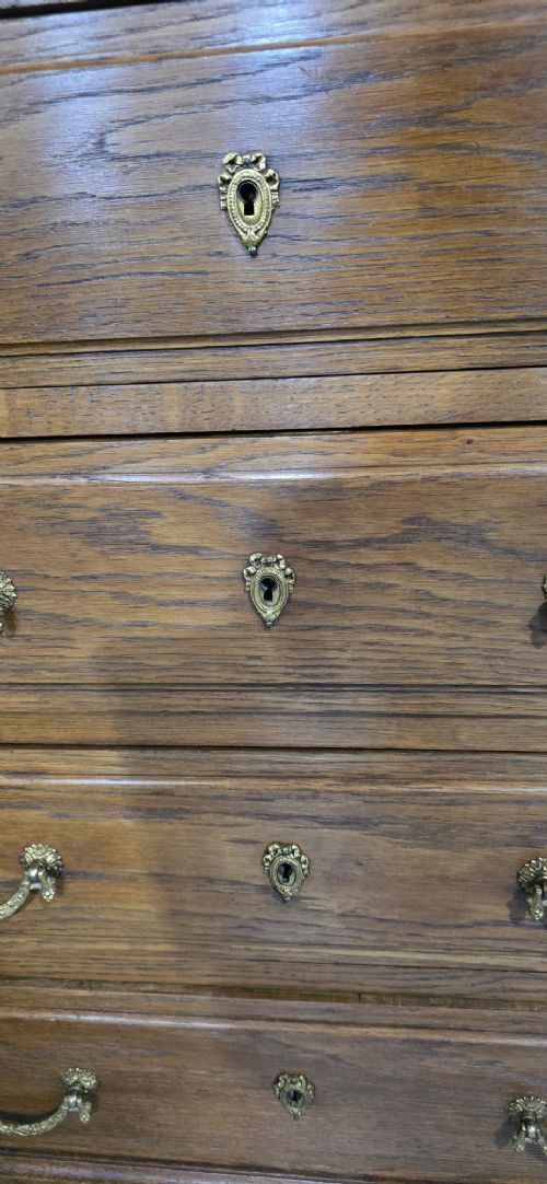 A tall French oak chest of drawers featuring six stacked drawers, brass swing handles, fluted side pilasters, and turned wooden feet. View III