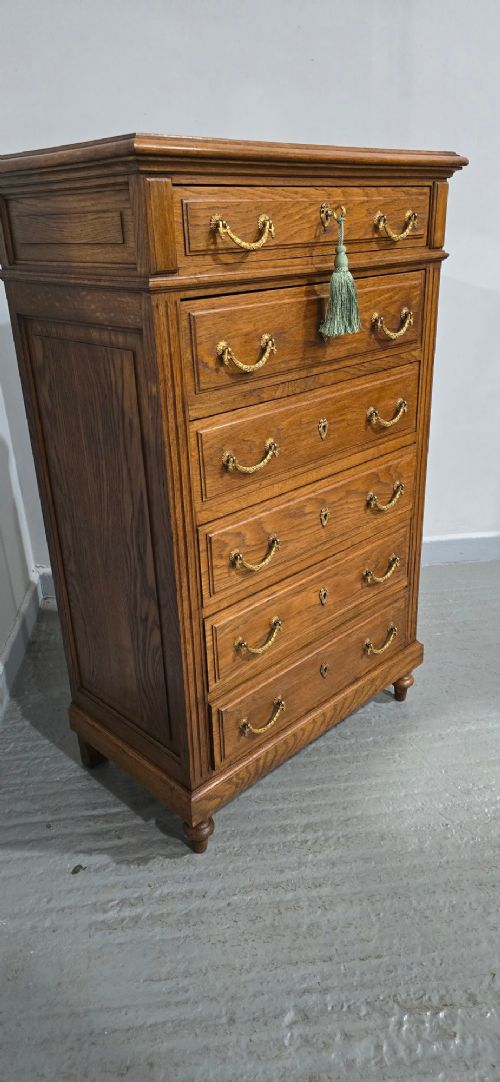 A tall French oak chest of drawers featuring six stacked drawers, brass swing handles, fluted side pilasters, and turned wooden feet. View VI