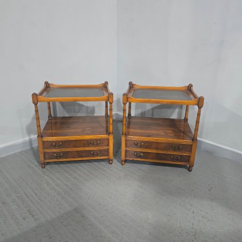 fig 1. A pair of yew wood lamp tables featuring dark green leather inset tops, a middle shelf, two drawers with brass handles, and turned corner columns.