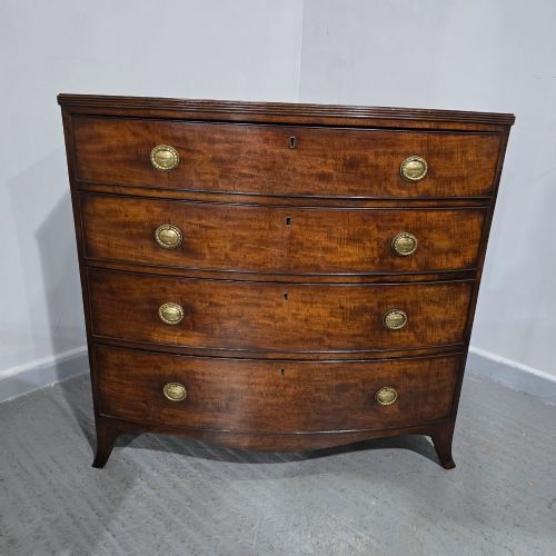 fig 1. A Georgian mahogany bowfront chest of drawers featuring four graduated drawers with oval brass handles and splayed feet.