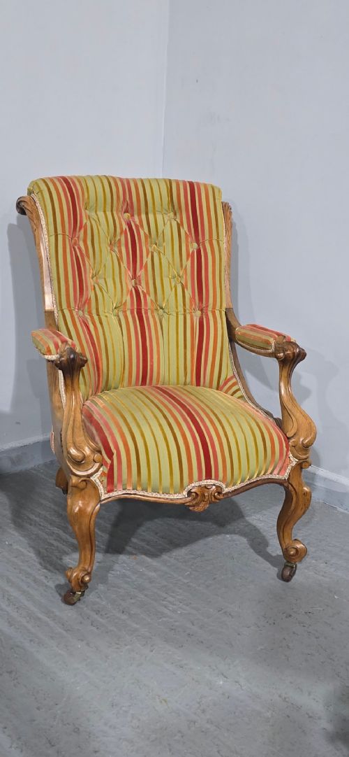 fig 1. A Regency style rosewood library armchair with button-tufted striped upholstery, carved scroll arms, cabriole legs, and brass castors.