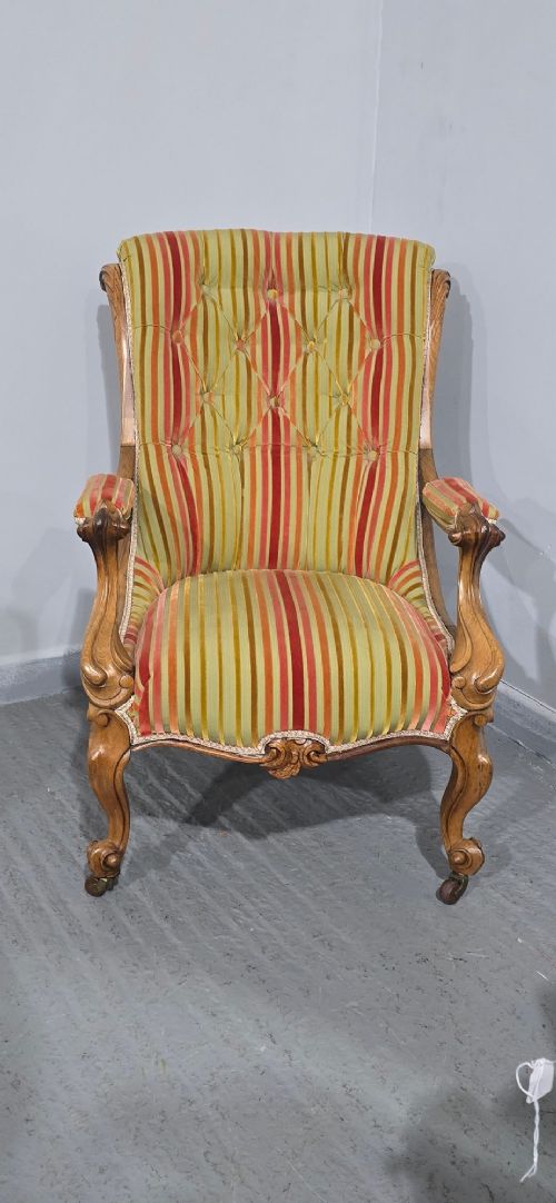 A Regency style rosewood library armchair with button-tufted striped upholstery, carved scroll arms, cabriole legs, and brass castors. View III