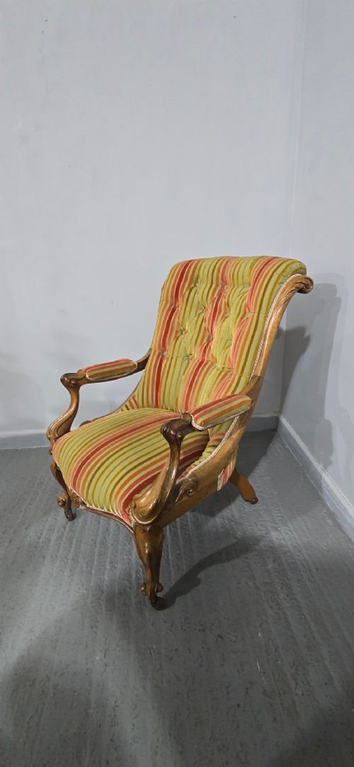 A Regency style rosewood library armchair with button-tufted striped upholstery, carved scroll arms, cabriole legs, and brass castors. View VIII