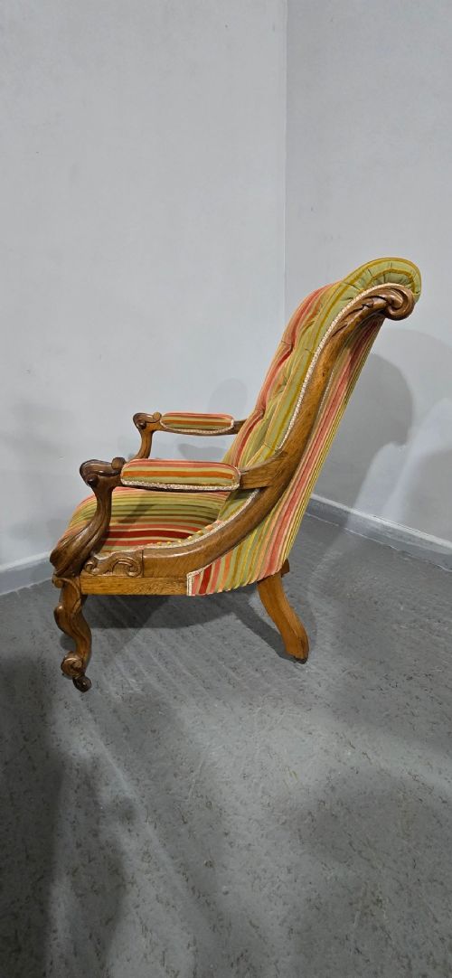 A Regency style rosewood library armchair with button-tufted striped upholstery, carved scroll arms, cabriole legs, and brass castors. View IX