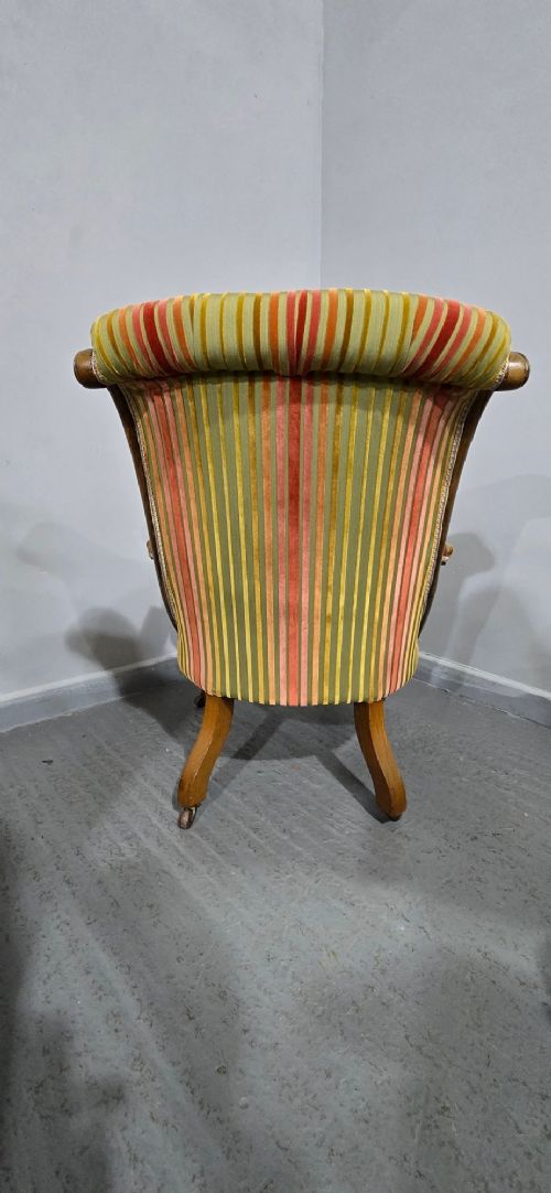 A Regency style rosewood library armchair with button-tufted striped upholstery, carved scroll arms, cabriole legs, and brass castors. View XI