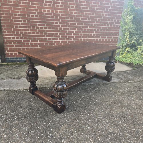 fig 1. A heavy dark oak refectory dining table featuring carved cup-and-cover bulbous legs and a low stretcher base.
