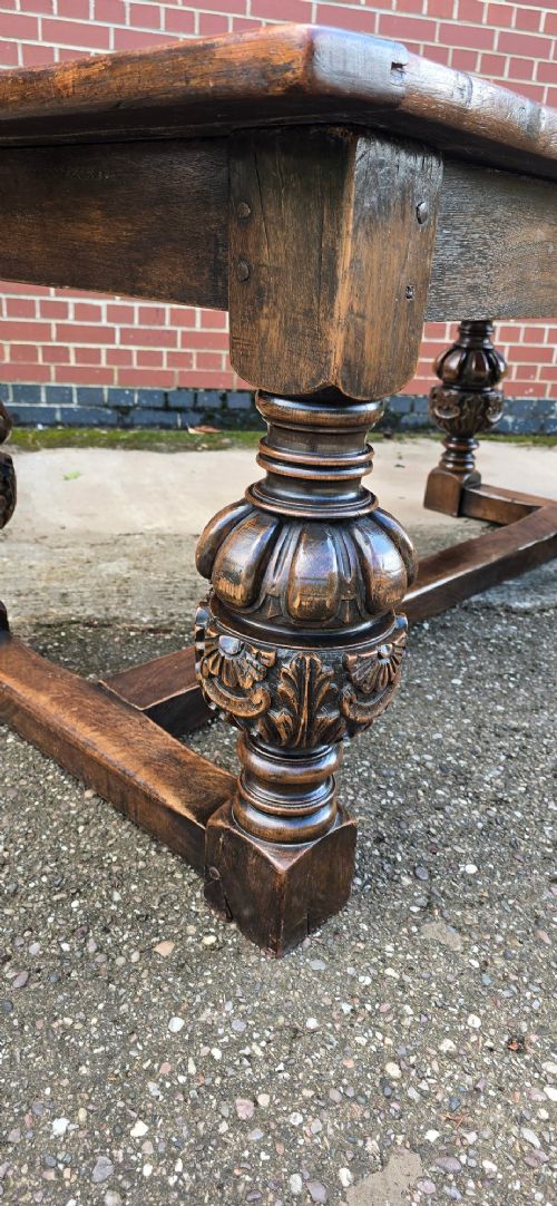 A heavy dark oak refectory dining table featuring carved cup-and-cover bulbous legs and a low stretcher base. View IV