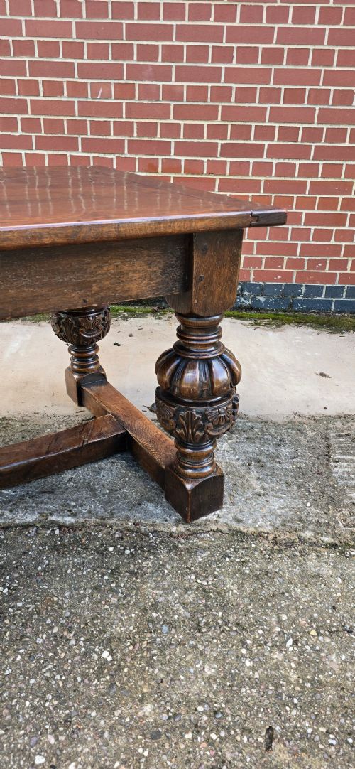 A heavy dark oak refectory dining table featuring carved cup-and-cover bulbous legs and a low stretcher base. View VII