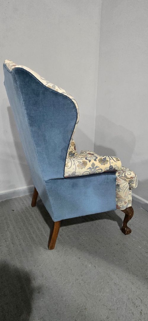 A high-backed wingback armchair upholstered in a botanical pattern with dark carved cabriole legs and ball-and-claw feet. View X