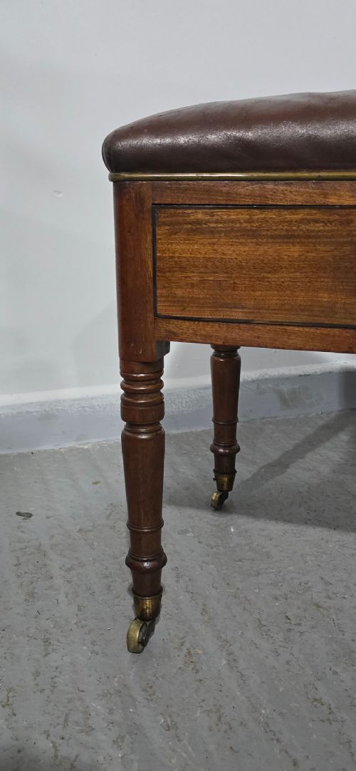 A Regency mahogany duet window stool with a brown leather seat, twin drawers, turned legs, and brass castors. View III