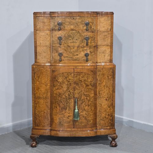 fig 1. An antique burr walnut linen press featuring an upper drawer section and lower double-door cupboard supported by carved ball and claw feet.