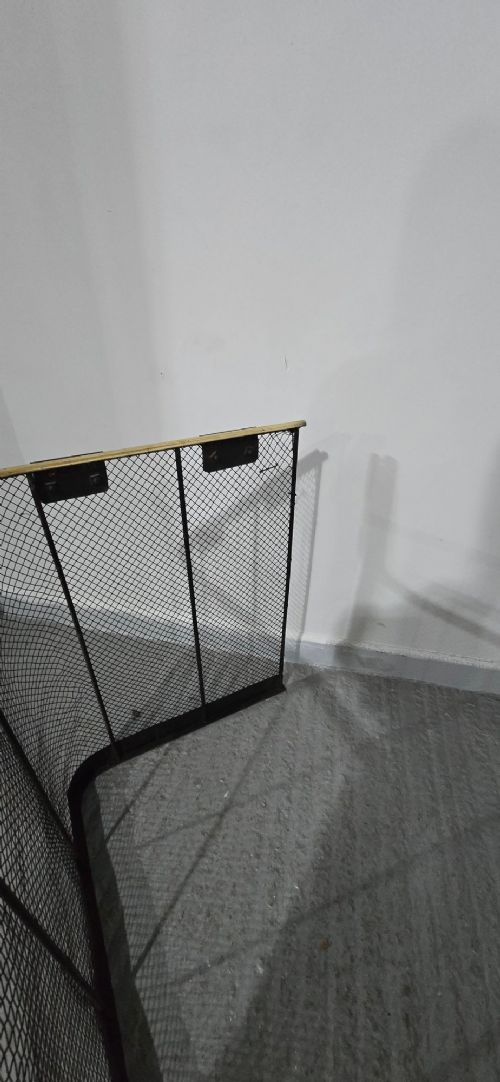 A three-sided black wire mesh fireguard featuring a polished brass rounded top rail and a solid base. View IX