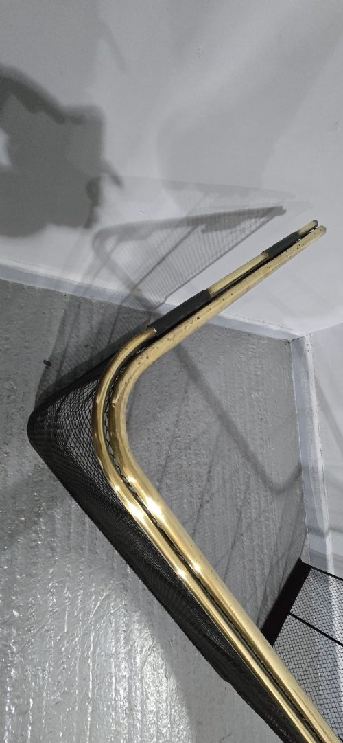 A three-sided black wire mesh fireguard featuring a polished brass rounded top rail and a solid base. View X